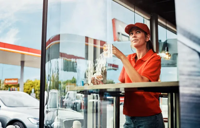 Woman enjoying her snacks and coffee in a Circle K café, looking out of a large window