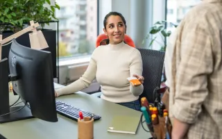 Woman in office at her desk excitedly showing someone her Circle K Pro card